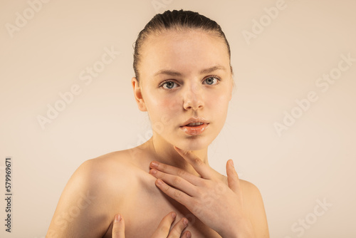 Lovely girl with clean skin. One hand under the neck, the other on the chest. Posing, beauty concept |