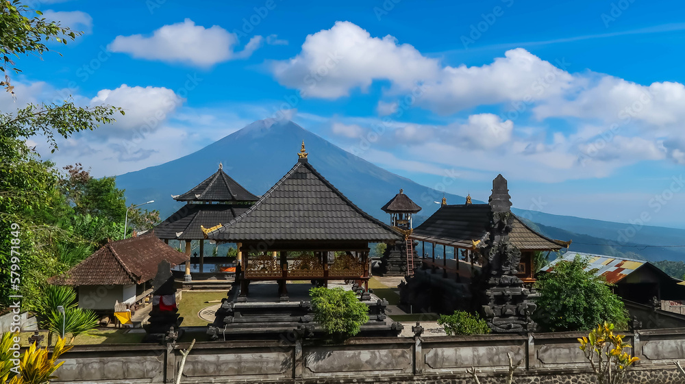 Balinese traditional building with temple or also called pura where Hindus pray and give offerings with Mount Agung background with blue sky and clouds