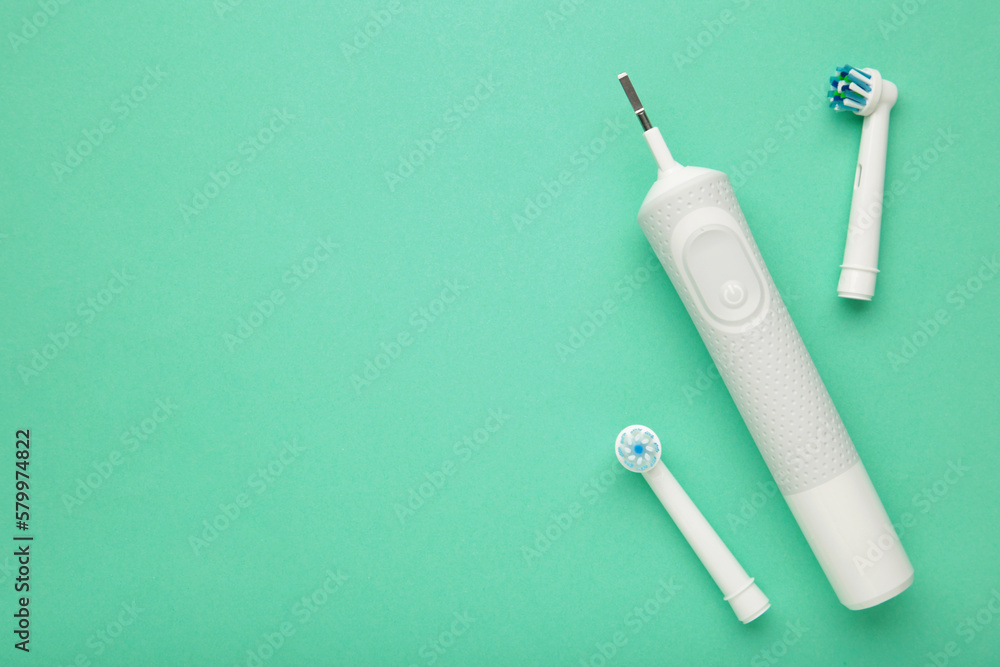Naklejka premium Modern electric toothbrush with a few spare heads on mint background