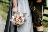 Trachtenhochzeit Brautpaar mit Brautdirndl und Lederhose und rosa Brautstrauß