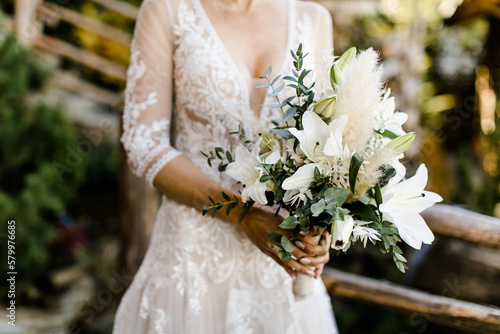Bride holds her wedding bouquet with lilies 