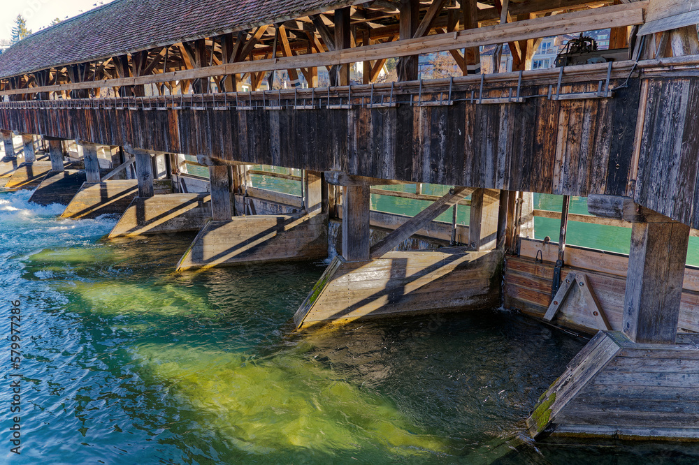 Scenic view of Aare River with close-up of barrier and covered wooden bridge at Swiss City of Thun on a sunny winter day. Photo taken February 21st, 2023, Thun, Switzerland. Scenic view of Aare River with close-up of barrier and covered wooden bridge at Swiss City of Thun on a sunny winter day. Photo taken February 21st, 2023, Thun, Switzerland.