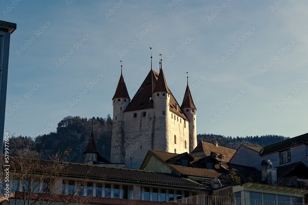 Old town of City of Thun with white castle on a hill in the background on a sunny winter day. Photo taken February 21st, 2023, Thun, Switzerland.