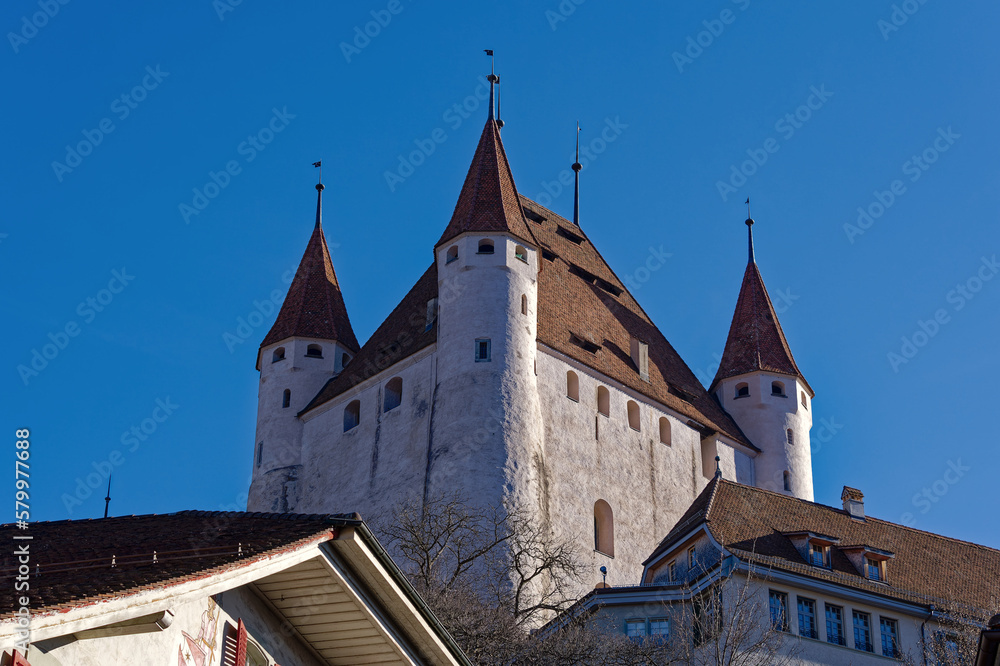 Old town of City of Thun with white castle on a hill in the background on a sunny winter day. Photo taken February 21st, 2023, Thun, Switzerland.