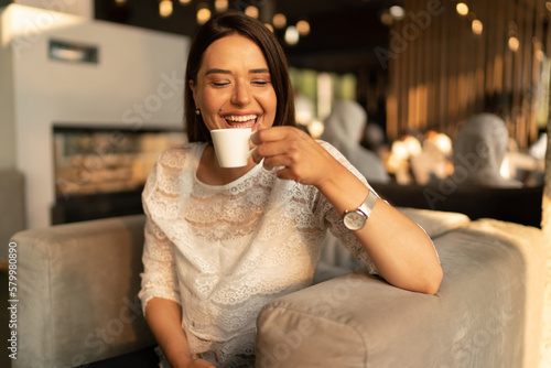 The smiling young woman drinks coffee 
