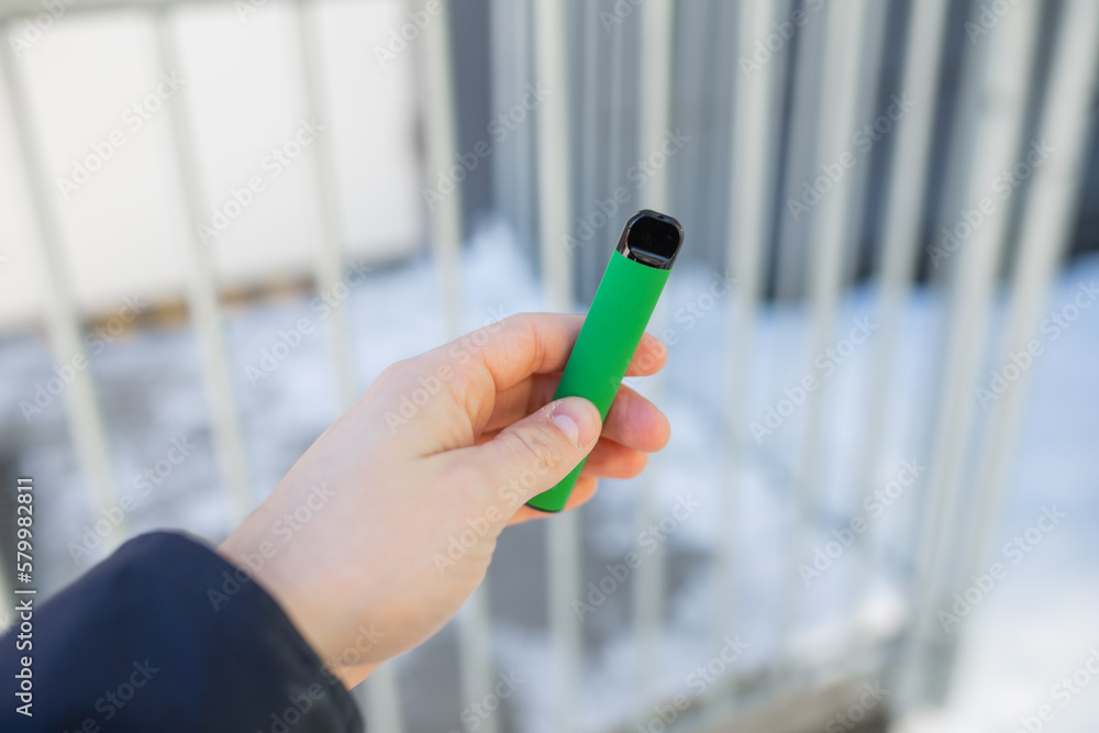 Man holding green electronic cigarette called vape pen Man holding green electronic cigarette called vape pen