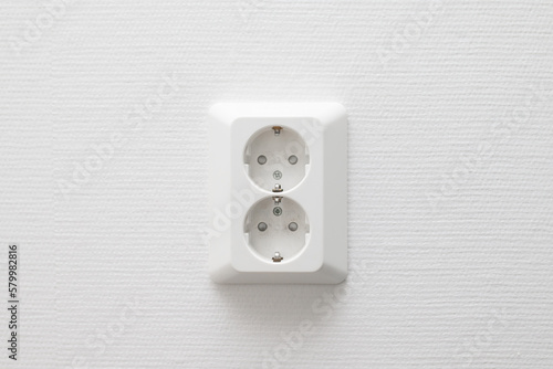 White electrical power outlet with two sockets on white wall