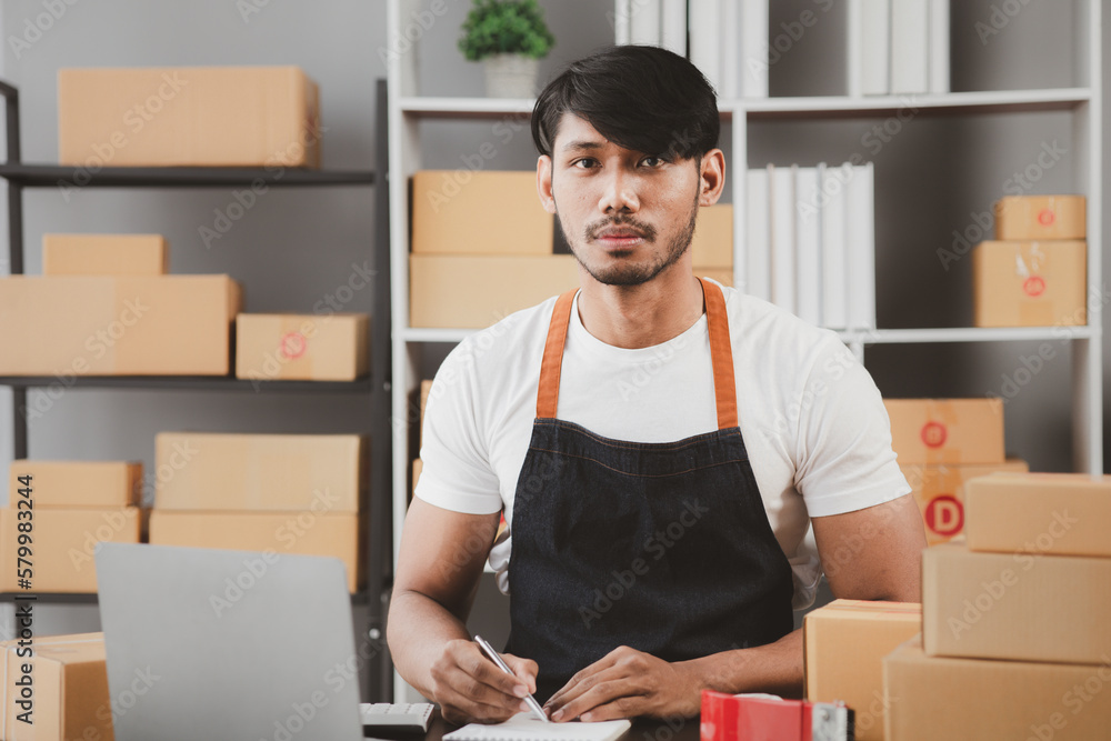 An Asian man owns an online store, he is an internet store operator selling products through an online shopping platform. The concept of selling goods and services on the internet. An Asian man owns an online store, he is an internet store operator selling products through an online shopping platform. The concept of selling goods and services on the internet.