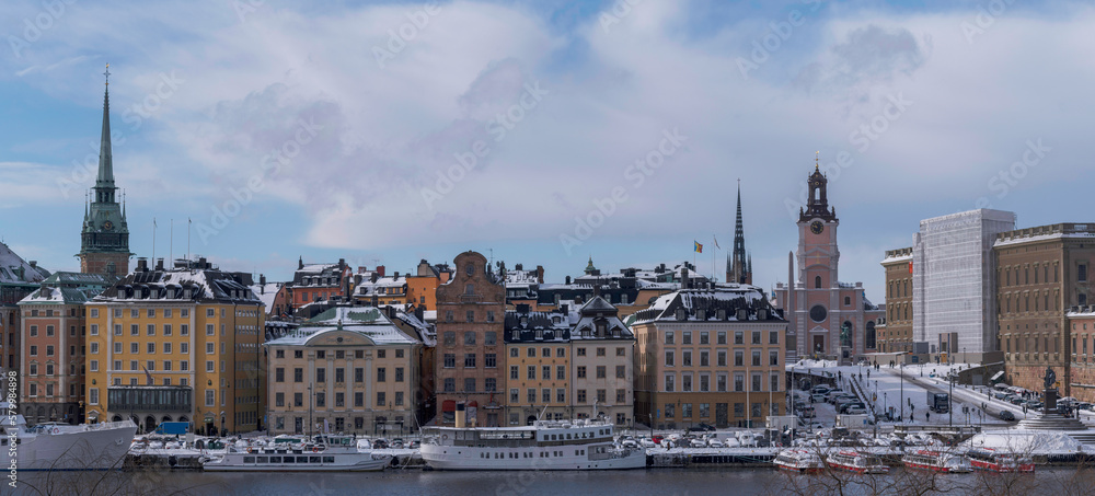Panorama, the old town Gamla Stan with churches, commuting and tourist boats, a snowy day in Stockholm