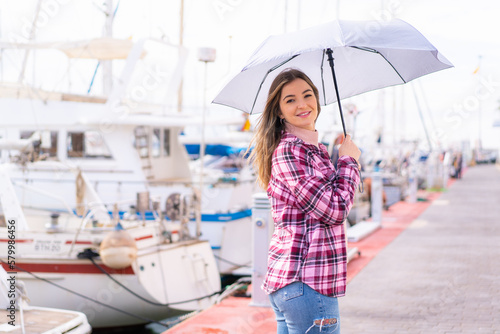 Young pretty Romanian woman holding an umbrella at outdoors