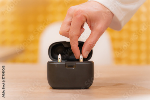 Hand of an audiologist doctor placing a hearing aid in its case.