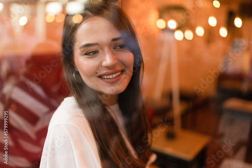 The young woman is sitting at the window in the coffee house and looks out 