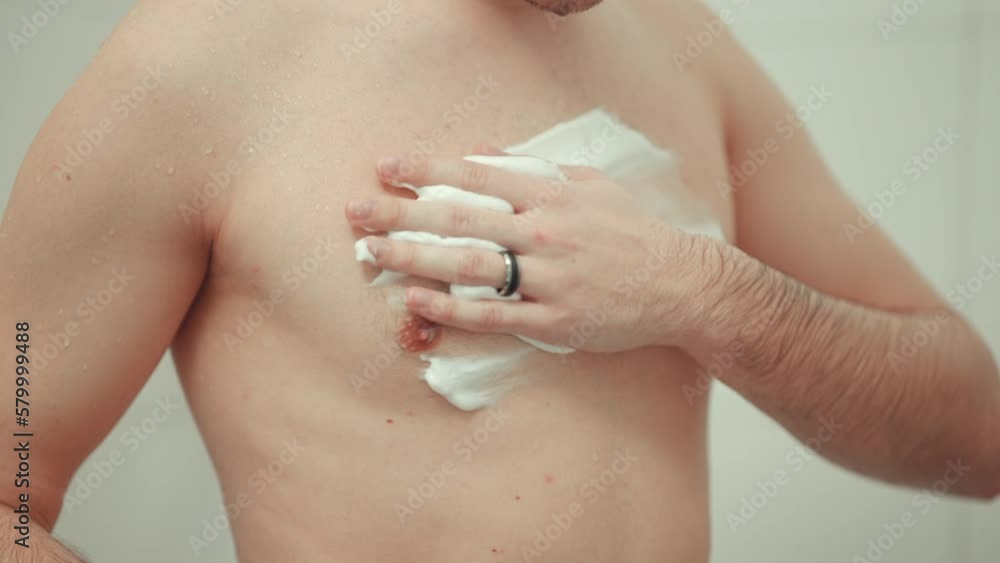 Young man applying shaving foam to his chest before shaving. Young man applying shaving foam to his chest before shaving.
