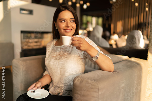 The smiling young woman drinks coffee 