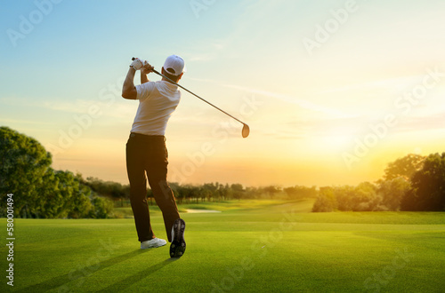 Golfer hit sweeping driver after hitting golf ball down the fairway with sunrise background.