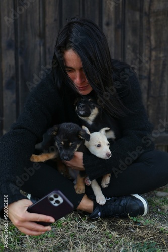 a beautiful girl  in a black sweater  holds street puppies in her arms  the girl takes care of the dogs  feeds them  spends time with them