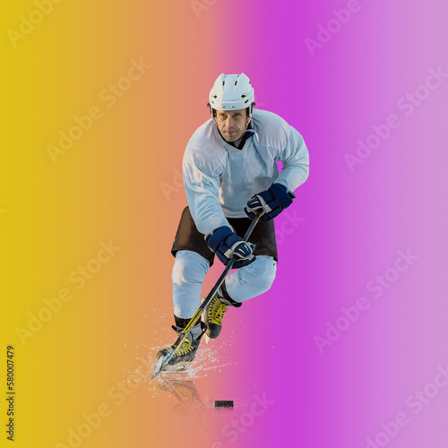 Professional ice hockey player hitting puck for winning goal in action on gradient multicolored neon background. Concept of sport competition.