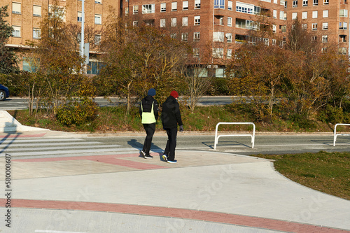 two men walk in sportswear next to a zebra crossing
