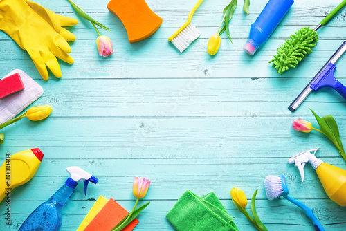 Flat lay composition with cleaning supplies, tools and spring flowers on colorful background