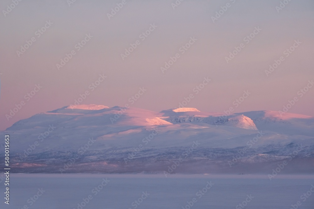 Obraz premium Beautiful sunrise at Abisko Ostra viewpoint. Snowy scenery of mountains. Abisko National Park (Abisko nationalpark), Sweden, Arctic Circle, Swedish Lapland