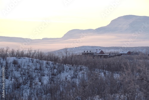 Beautiful sunrise at Abisko Ostra viewpoint. Snowy scenery of mountains and buildings in valley. Abisko National Park (Abisko nationalpark), Sweden, Arctic Circle, Swedish Lapland