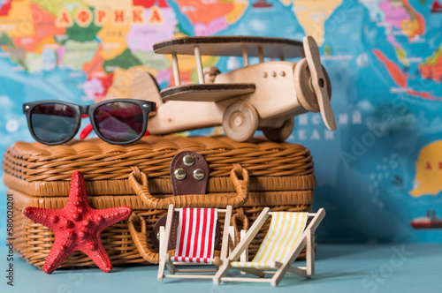 Tourism. A model of a vintage air plane, deck chairs and a suitcase on the background of a world map. The concept of travel, adventure and discovery.