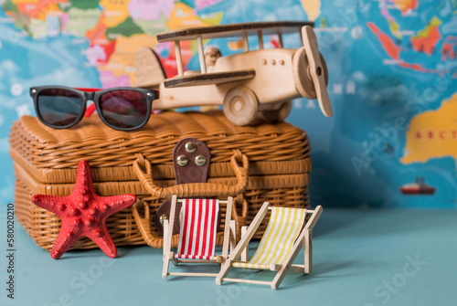 Tourism. A model of a vintage air plane, deck chairs and a suitcase on the background of a world map. The concept of travel, adventure and discovery.