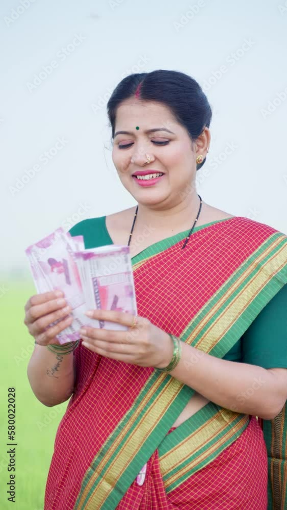 vertical shot of Happy smiling woman counting money near green farmland - concept of Earnings, banking or finanical support and woman empowerment or growth vertical shot of Happy smiling woman counting money near green farmland - concept of Earnings, banking or finanical support and woman empowerment or growth