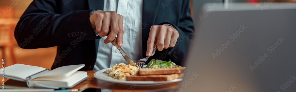 Close up of businessman taking a breakfast before starting working day in cafe