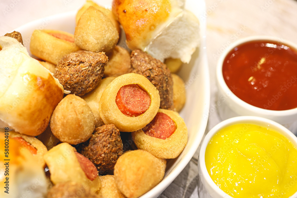 Salgados brasileiros variados dentro de uma assadeira e potes com