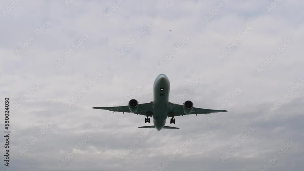 Wide body airliner landing at Phuket Airport. Airplane overhead. Tourists on the beach taking pictures on the background of the airliner Wide body airliner landing at Phuket Airport. Airplane overhead. Tourists on the beach taking pictures on the background of the airliner