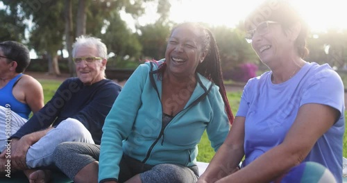 Multiracial senior people having fun after workout exercises outdoor with city park in background - Healthy lifestyle and joyful elderly lifestyle concept