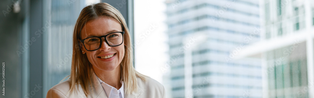 Smiling businesswoman in glasses drinking coffee and making notes while working in cafe Smiling businesswoman in glasses drinking coffee and making notes while working in cafe