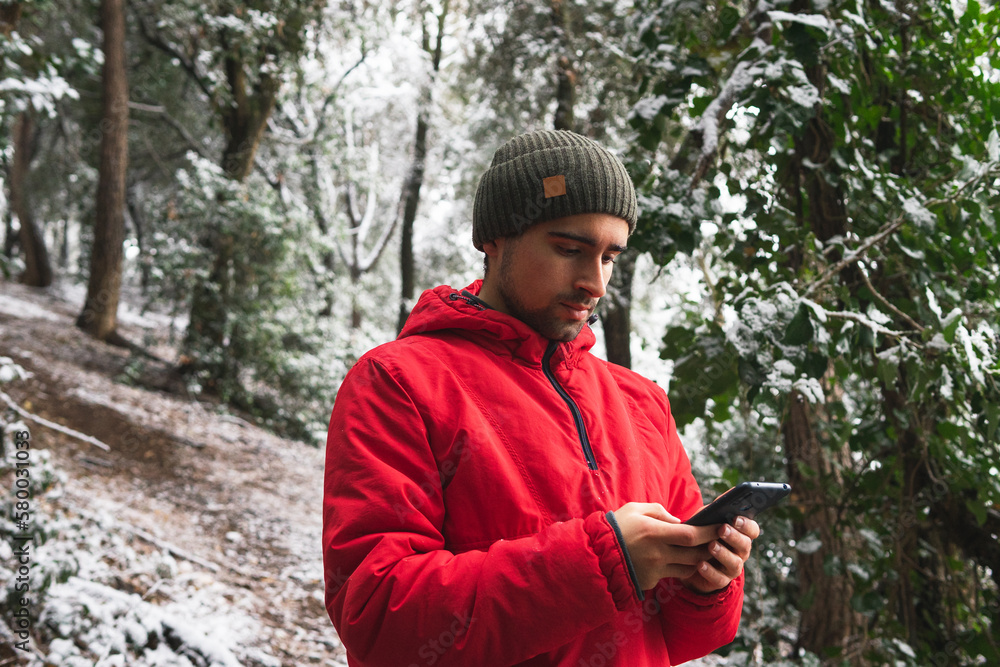 Young man standing and using smartphone in forest Young man standing and using smartphone in forest