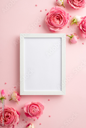 Women's Day concept. Top view vertical photo of photo frame pink peony roses and sprinkles on isolated pastel pink background with copyspace
