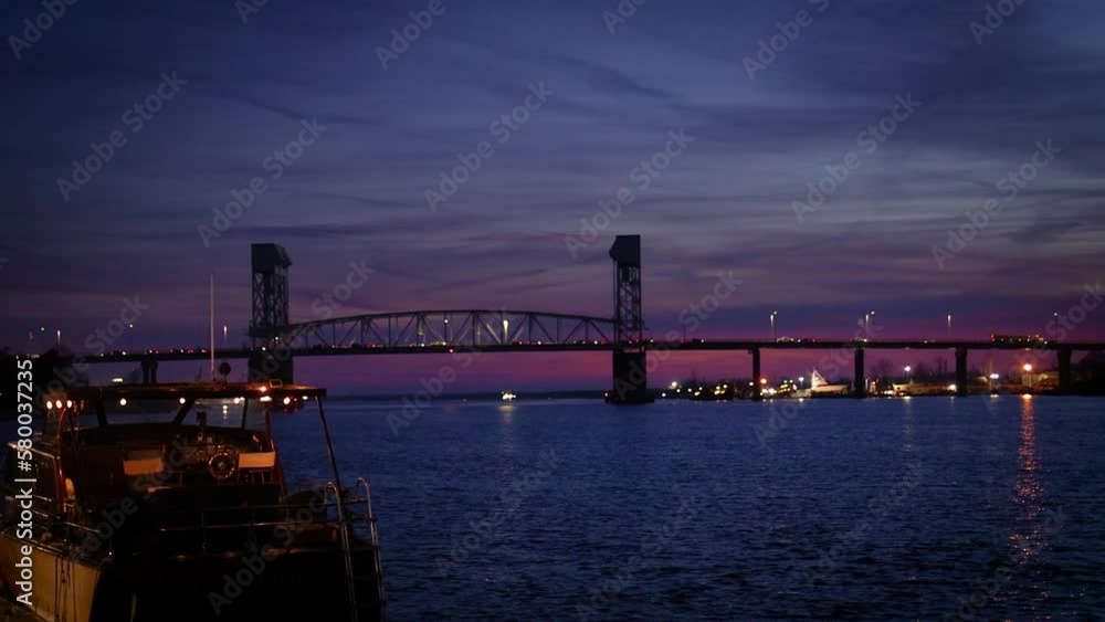 river embankment in evening light with moored boat and drawbridge on the background. Downtown riverwalk in Wilmington, NC, USA. Cape Fear River river embankment in evening light with moored boat and drawbridge on the background. Downtown riverwalk in Wilmington, NC, USA. Cape Fear River
