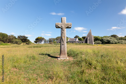 Grosse croix de granit, manoir en arrière-plan, herbe et ciel bleu