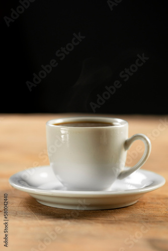 Coffee cup and coffee beans on wooden table. Black background.