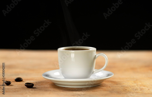 Coffee cup and coffee beans on wooden table. Black background.