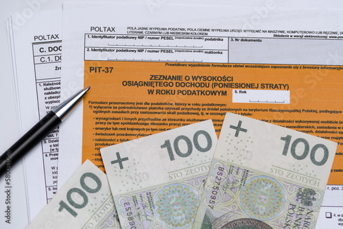 Formularz podatkowy zeznania rocznego pit 37 z długopisem i wachlarzem z polskiej gotówki  photo