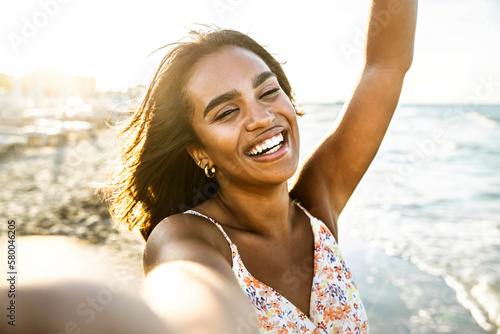 Beautiful black young woman taking selfie picture walking on the beach - Delightful female smiling at camera outside - Summer vacation, technology and healthy lifestyle concept