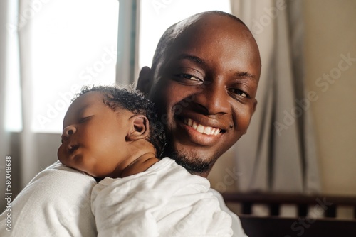 Happy african father holding his newborn looking at camera.