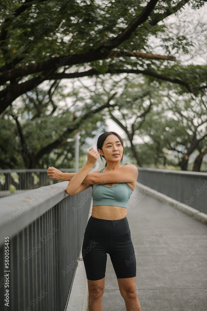 Asian happy woman exercise in park on morning. Healthy female wearing sportswear and stretching body before running in outdoors. wellness lifestyle, outside activities. Asian happy woman exercise in park on morning. Healthy female wearing sportswear and stretching body before running in outdoors. wellness lifestyle, outside activities.