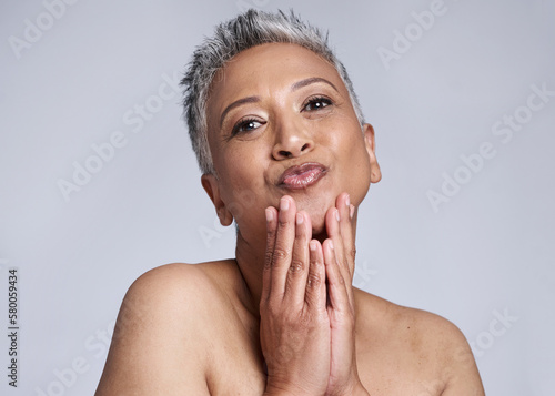 Face, skincare and pout with a mature woman in studio on a gray background to promote natural beauty. Portrait and wellness with a senior female inside to model antiaging treatment or care photo