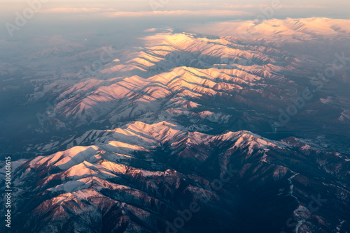 Aerial high altitude view of mountain range crossed by shadows from rising sun  Caucasus  Georgia