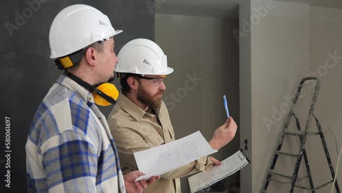 Side view, two engineers at a construction site using pens and a drawing explain the method of installing the device. Explanation of improvised objects at the construction site. High quality 4k