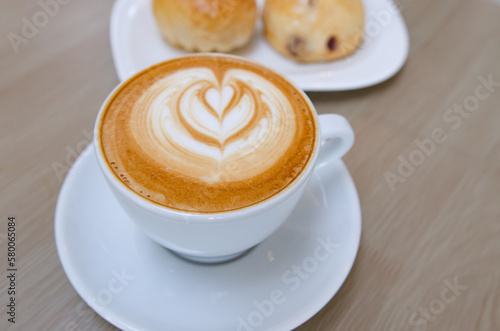 A wooden table with a fragrant cappuccino and baked bread