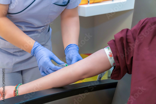 Nurse taking blood sample from young female patient in the background. Selective focus on sample tube. The doctor or nurse will take a blood sample from a vein for testing injection probe vein blood photo