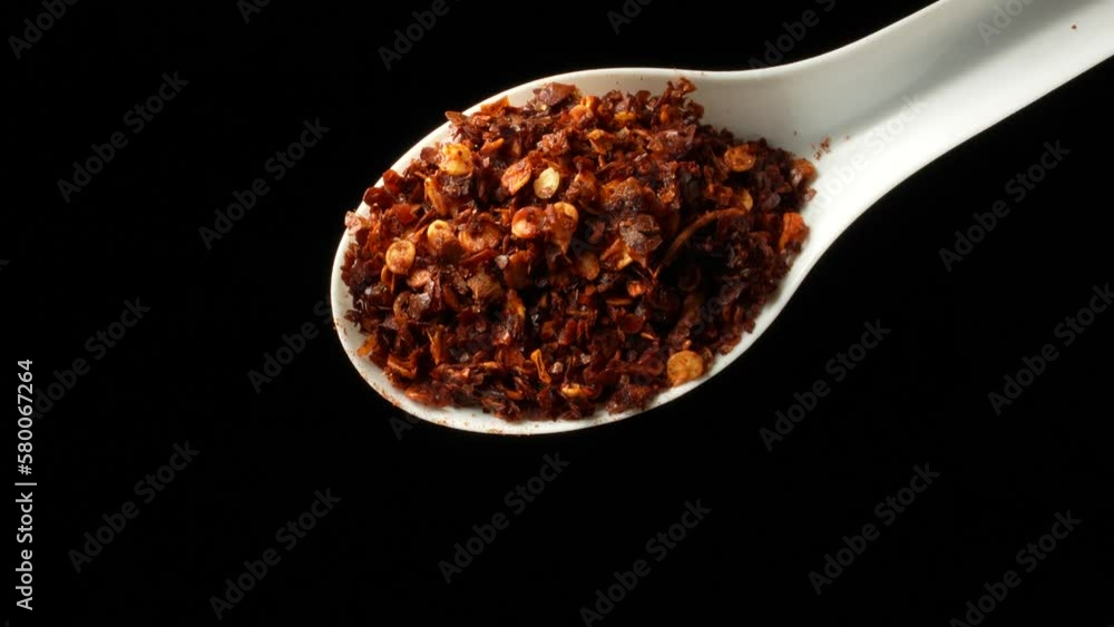 Chili pepper. A full spoon of ground chili pepper on black background in slow motion. Chili pepper. A full spoon of ground chili pepper on black background in slow motion.