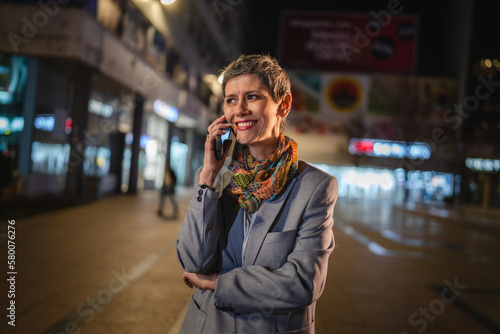 Senior woman use mobile phone talk make a call in the city at night